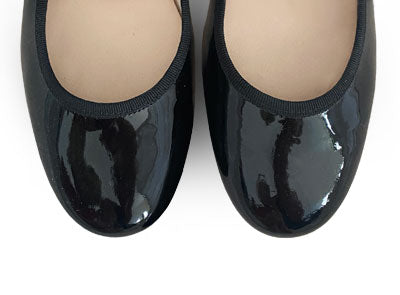 Black patent leather ballet flats with strap and heel